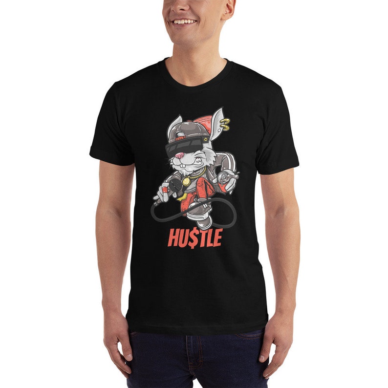 May include: Black t-shirt with a cartoon rabbit wearing a hat, sunglasses, and a gold chain. The rabbit is holding a microphone and a dollar bill. The text "HUSTLE" is printed below the rabbit.