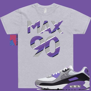 May include: A grey t-shirt with the text "MAX 90" in purple, white, and grey stripes. The shirt is paired with white, grey, and purple Nike Air Max 90 sneakers.