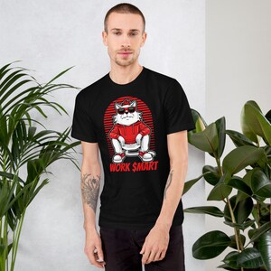 Puede incluir: Camiseta negra con un gato blanco que lleva gafas de sol rojas y una sudadera roja sentado en un inodoro. El gato tiene un fondo rojo y blanco a rayas detr&aacute;s de &eacute;l. El texto "WORK $MART" est&aacute; impreso debajo del gato.