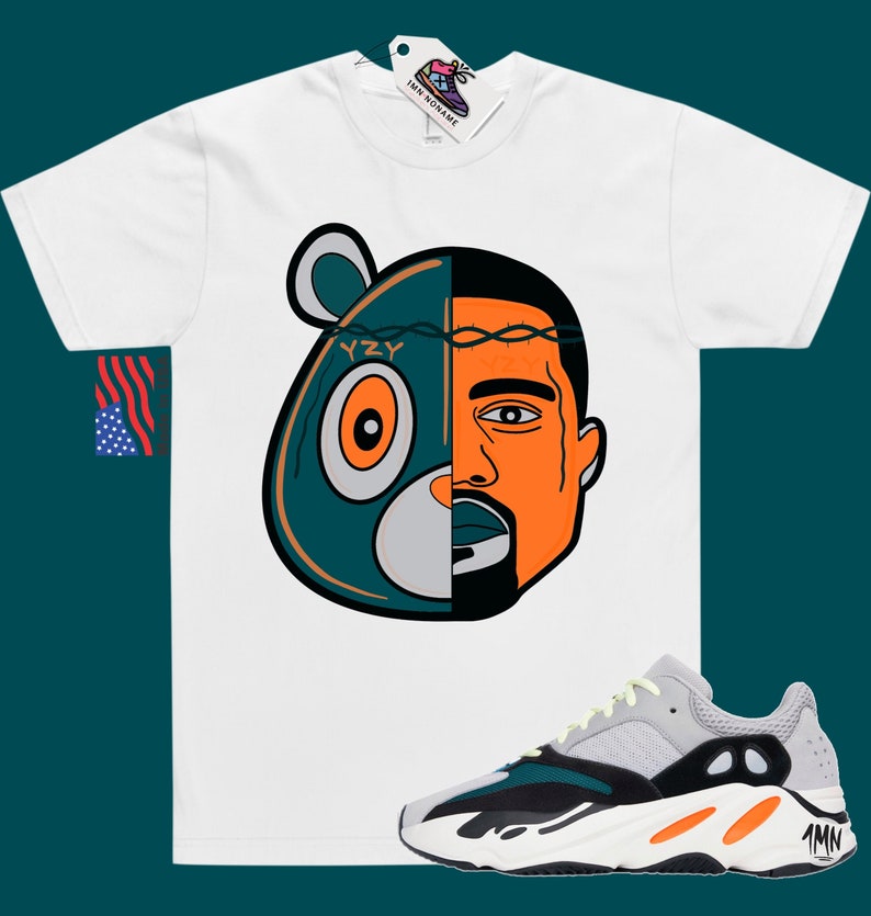 May include: White t-shirt with a graphic of a teal bear head with a barbed wire crown and Kanye West's face on the right side. The graphic says "YZY". A pair of grey, black, and orange Yeezy 700 sneakers are shown below the t-shirt.