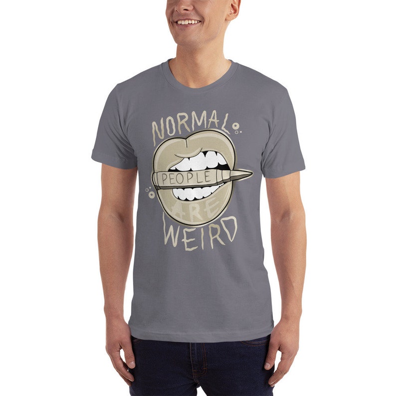Pode incluir: Uma camiseta cinza com um gr&aacute;fico de uma boca com um l&aacute;pis que diz "As pessoas s&atilde;o estranhas". O texto "Normal." est&aacute; acima da boca e o texto "WEIRD" est&aacute; abaixo da boca.