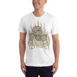 May include: White t-shirt with a graphic of a person wearing a ski mask and a gold chain, with flames behind them. The text "YZY MONEY" is printed below the graphic.