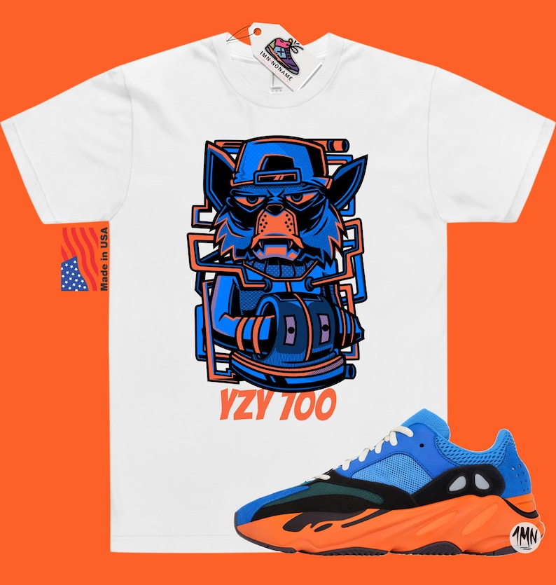 Puede incluir: Camiseta blanca con un gr&aacute;fico de lobo de dibujos animados azul y naranja y el texto "YZY 700". Un par de zapatillas azules, naranjas y verdes con el texto "1MN" en el lateral.