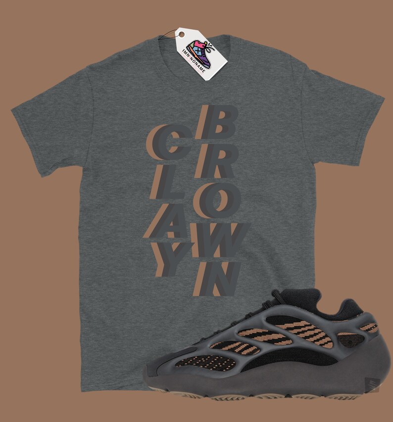 May include: A dark gray t-shirt with the word "CROWAY" in a layered, 3D design. A matching dark gray and tan sneaker is positioned below the shirt. A tag with a shoe graphic hangs from the shirt.