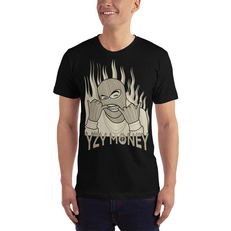 May include: Black t-shirt with a graphic of a person wearing a ski mask and gold chains, with flames behind them. The text "YZY MONEY" is printed below the graphic.