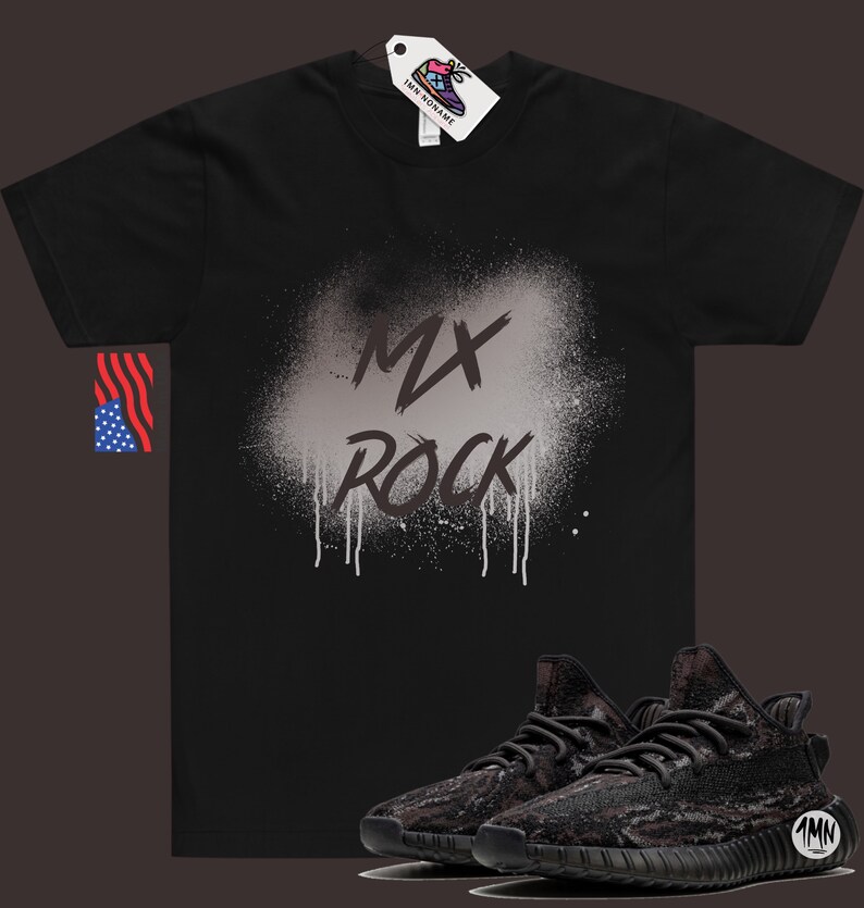 以下が含まれることがあります： 白いスプレーペイントのデザインで「MX Rock」と書かれた黒いTシャツ。Tシャツの下には、黒と茶色の迷彩柄のスニーカーが1足あります。