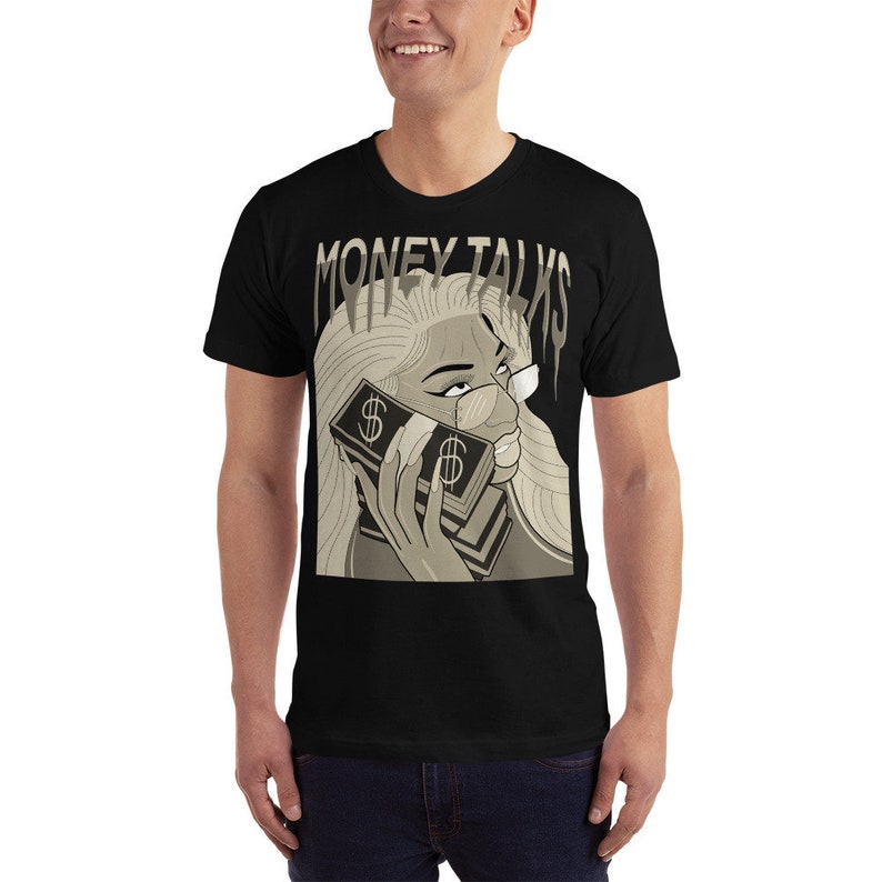 May include: Black t-shirt with a graphic print of a woman with blonde hair holding a stack of money to her ear. The text "MONEY TALKS" is printed above the woman's head.