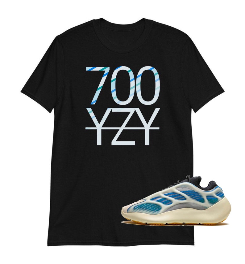 May include: Black t-shirt with the text "700 YZY" in blue and white stripes. A white and blue sneaker with a beige sole is in the bottom right corner of the image.