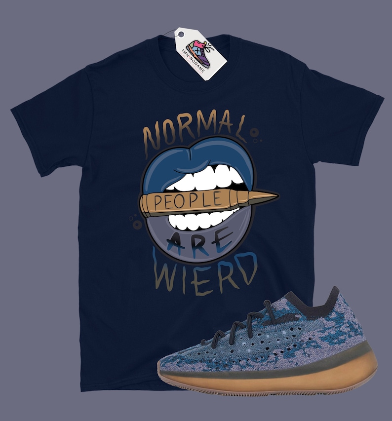 Op de afbeelding: Een donkerblauw t-shirt met een afbeelding van een mond met een kogel waarop staat "Mensen zijn raar". Een paar blauwe en bruine sneakers bevinden zich in de rechterbenedenhoek van de afbeelding.