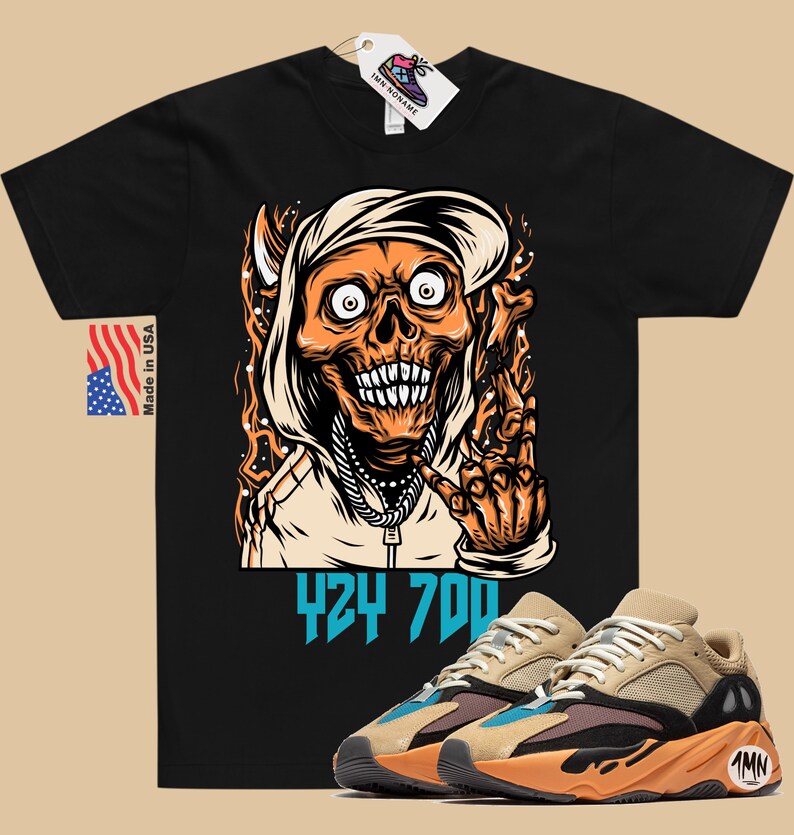 May include: Black t-shirt with a cartoon illustration of a skull wearing a hoodie and making a hand gesture. The text "424 700" is printed below the illustration. A pair of tan, orange, and blue sneakers are shown below the t-shirt.