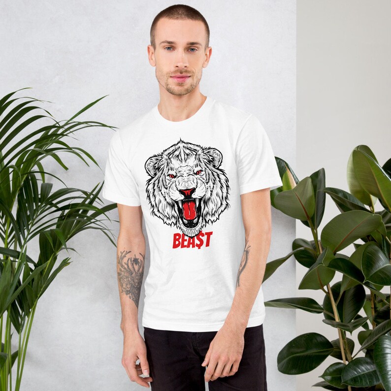 May include: White t-shirt with a black and white illustration of a roaring lion's head. The lion has a red tongue and the word "BEAST" is printed in red below the lion's head.