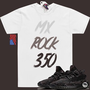 Puede incluir: Camiseta blanca con el texto "MY ROCK 350" en letras grises y negras en forma de pinceladas. Debajo de la camiseta se muestra un par de zapatillas de deporte de camuflaje negro y marr&oacute;n con suela negra.