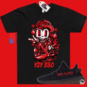 May include: Black t-shirt with a red cartoon character skateboarding and the text "YZY 350". A pair of black and red Yeezy 350 sneakers are shown below the t-shirt.