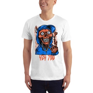 May include: White t-shirt with a graphic of a red skull wearing a blue hoodie and a backwards hat. The skull is holding a bone in its right hand and has the text "424 700" printed below it.