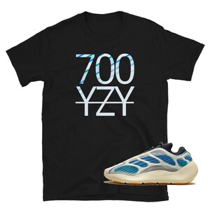 May include: Black t-shirt with white text that says "700 YZY" and a pair of white and blue sneakers with a black sole.