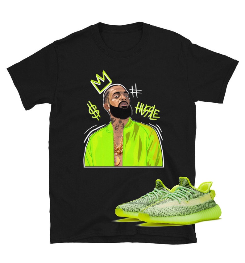 Puede incluir: Camiseta negra con una ilustraci&oacute;n verde de un hombre que lleva una chaqueta verde y una corona. El texto '#HUSTLE' est&aacute; escrito en verde. Un par de zapatillas de deporte de color verde ne&oacute;n se muestran debajo de la ilustraci&oacute;n.