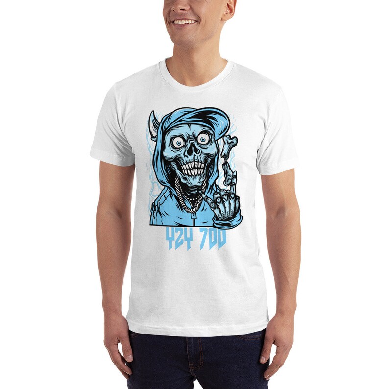 May include: White t-shirt with a blue graphic of a skull wearing a blue hoodie and hat. The skull is giving the middle finger and the text "424 700" is below the skull.