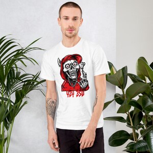 May include: White t-shirt with a graphic of a skull wearing a red hoodie and making a rude gesture. The text "424 350" is printed below the skull.