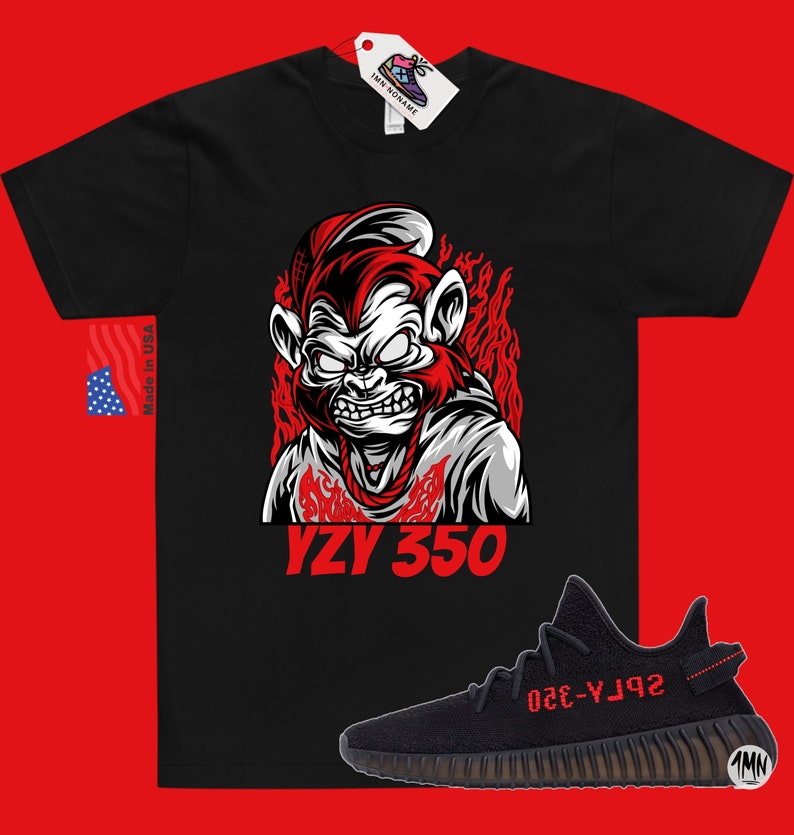 May include: Black t-shirt with a red and white illustration of a monkey wearing a hat and a chain. The text "YZY 350" is printed below the monkey. A black and red Yeezy 350 shoe is shown below the t-shirt.