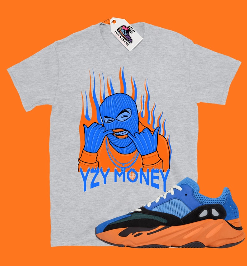 May include: A gray t-shirt with a blue and orange illustration of a person wearing a ski mask and the text "YZY MONEY". A pair of blue and orange sneakers are also pictured.