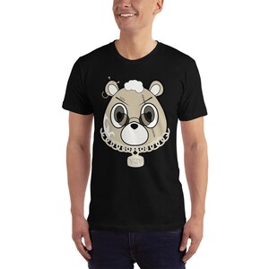 May include: Black t-shirt with a cartoon image of a brown bear wearing a gold chain and a tag that says "AZN" on it. The bear has stitches on its face and a gold hoop earring.
