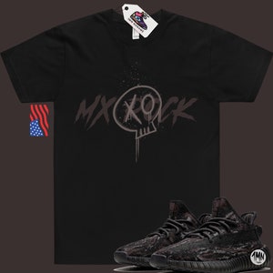 May include: Black t-shirt with a skull graphic and the text "MXROCK" printed on the front. A pair of black and grey camouflage sneakers are also pictured.