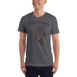 K&ouml;nnte beinhalten: Ein dunkelgraues T-Shirt mit einer Grafik einer Hand, die Geld in einer betenden Position h&auml;lt. Der Text "Make It Rain" ist in dunkelroter Schrift &uuml;ber der Grafik gedruckt.