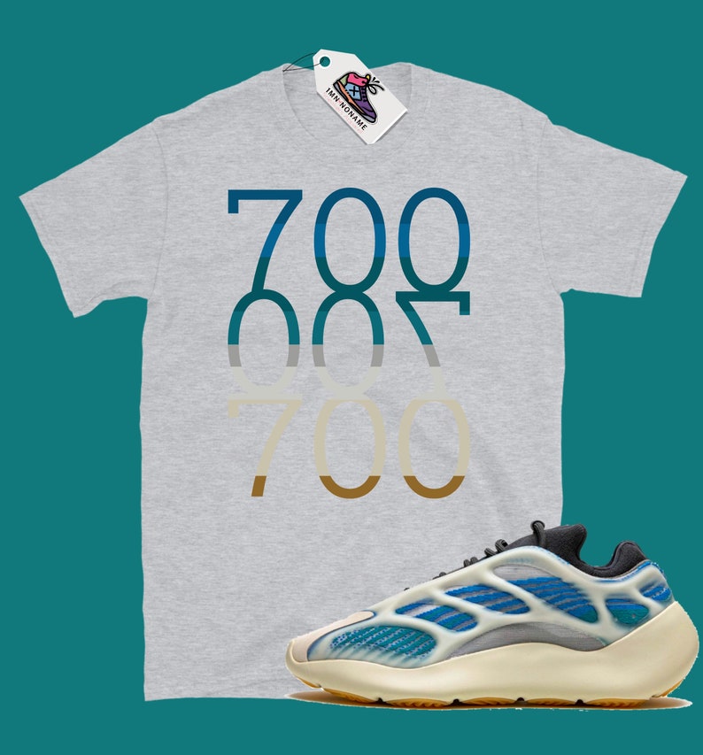 May include: A grey t-shirt with the number 700 printed in a gradient of blue, grey, and brown. A pair of white and blue trainers with a black sole.