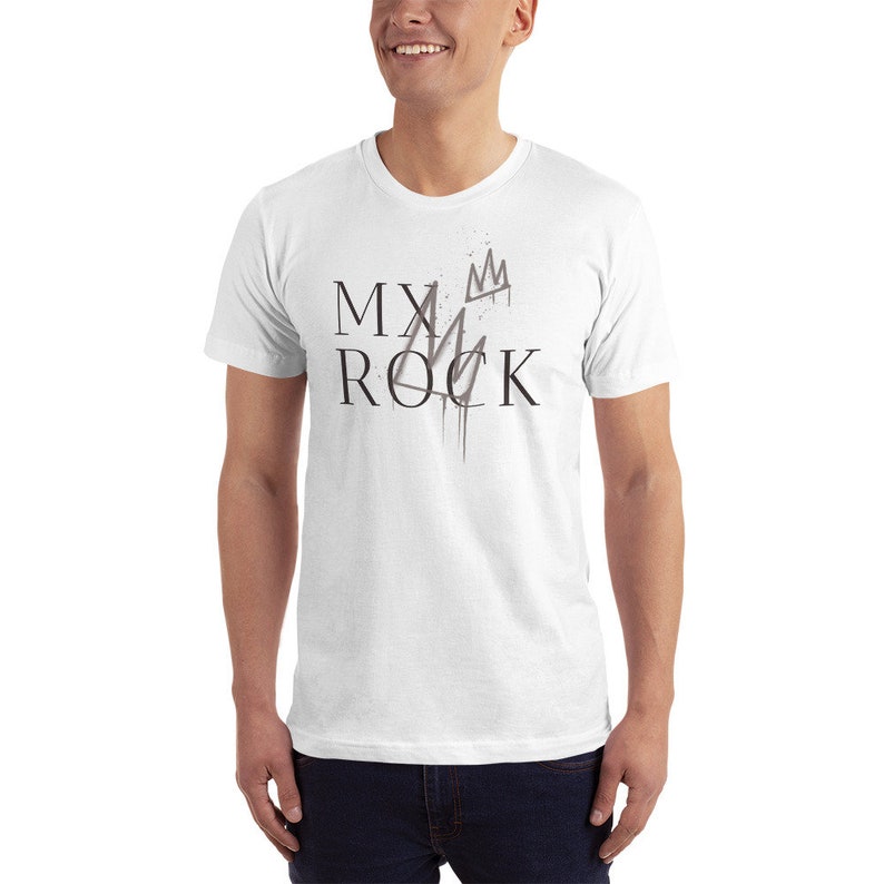 May include: White t-shirt with black text that reads "MY ROCK" and a stylized crown graphic.