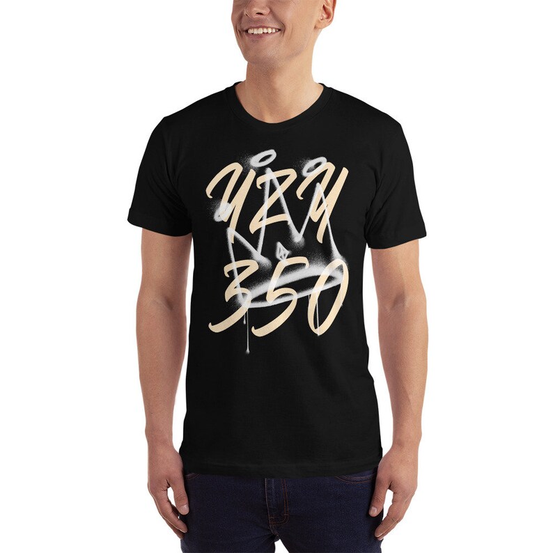 May include: Black t-shirt with a white and beige spray paint design of a crown and the text "Yeezy 350".