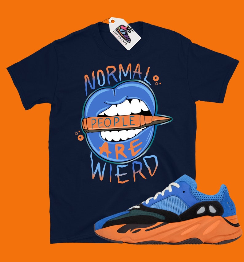 May include: A navy blue t-shirt with a graphic of a blue mouth with teeth biting a bullet that says "People are weird". The shirt is paired with orange and blue sneakers.