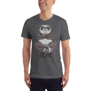 Peut inclure: Un t-shirt gris fonc&eacute; avec un panda dessin anim&eacute; portant des baskets et assis les bras crois&eacute;s. Le panda est blanc et gris avec des yeux noirs et un nez noir. Le texte "DOPE" est imprim&eacute; sous le panda.