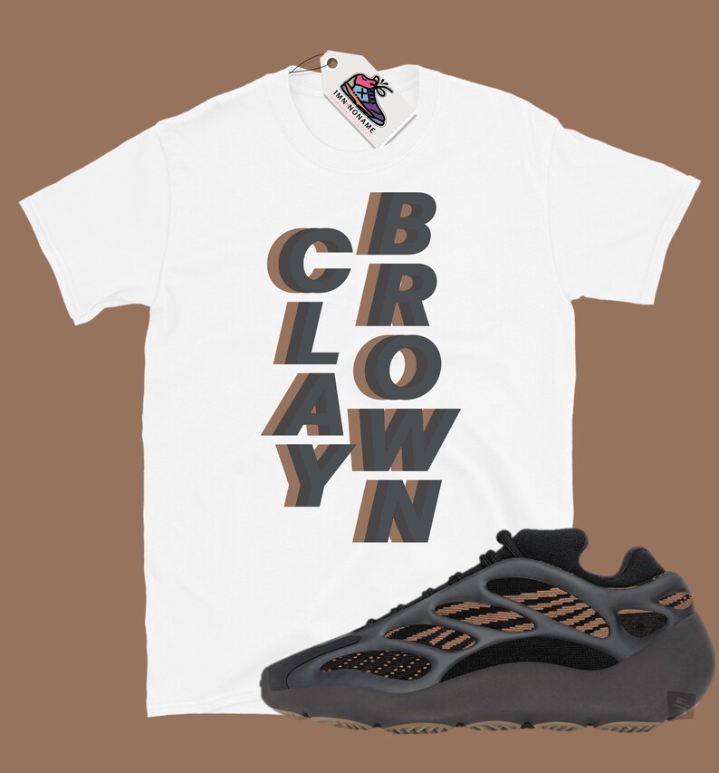 May include: White t-shirt with the word "CBRAYWN" in layered gray and brown letters. A black and brown athletic shoe is next to the shirt. A tag with a shoe logo hangs from the shirt.