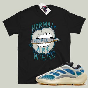May include: Black t-shirt with a graphic of a mouth with a crayon that says "People are weird".  The t-shirt is paired with white and blue sneakers.