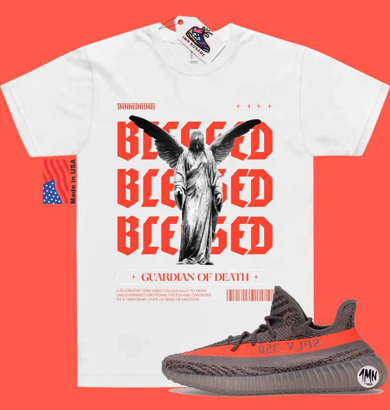 May include: White t-shirt with a red graphic of an angel with wings and the text "Blessed" repeated three times. The text "Guardian of Death" is below the graphic. A pair of gray and orange sneakers are in the bottom right corner of the image.