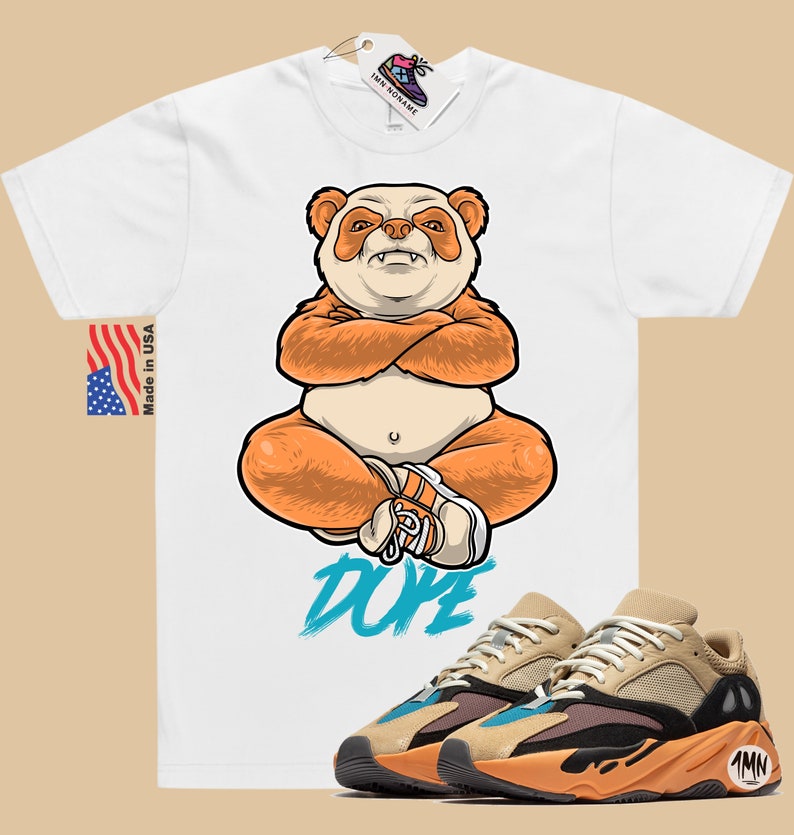 Puede incluir: Camiseta blanca con un panda de dibujos animados que lleva zapatos naranjas y la palabra "DOPE" impresa en azul. Un par de zapatillas de deporte de color beige, naranja y negro con una raya azul y el n&uacute;mero "700" en el lateral.