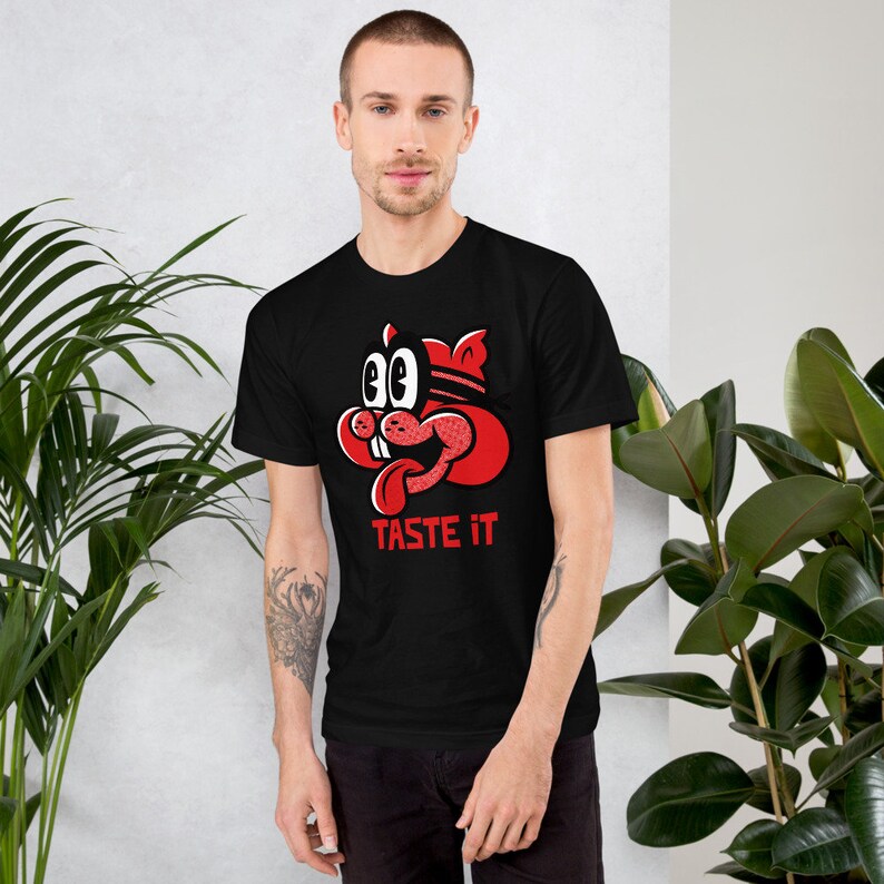 May include: Black t-shirt with a red cartoon character with a tongue sticking out and the text "TASTE IT" underneath.