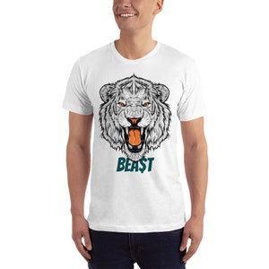 May include: White t-shirt featuring a graphic of a roaring white lion's head with the word "BEAST" in teal underneath.