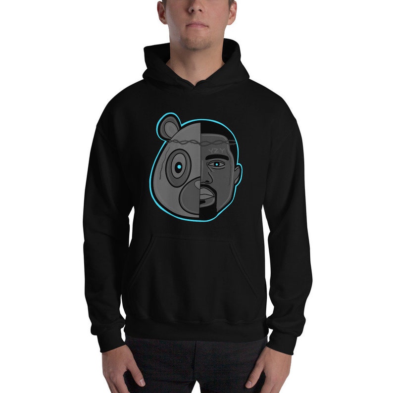 Peut inclure: Sweat-shirt &agrave; capuche noir avec un motif repr&eacute;sentant une t&ecirc;te d'ours et un visage d'homme, divis&eacute;s en deux. L'ours est gris et le visage de l'homme est noir et blanc. Le motif est soulign&eacute; de bleu.