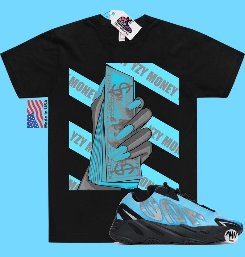 May include: Black t-shirt with a graphic of a hand holding a stack of blue bills with the text "YZY MONEY" on it.  A pair of black and blue sneakers with the text "YZY" on the side are in the bottom right corner of the image.