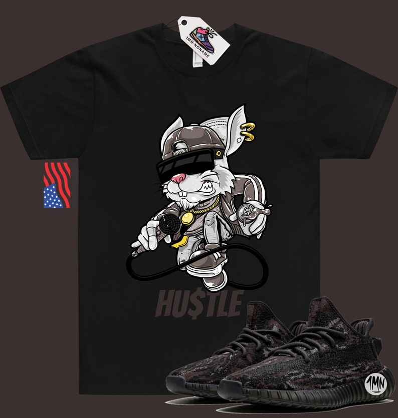 May include: Black t-shirt with a cartoon rabbit wearing sunglasses and a hat, holding a microphone. The text "HUSTLE" is below the rabbit. A pair of black and brown camouflage sneakers are in the bottom right corner of the image.