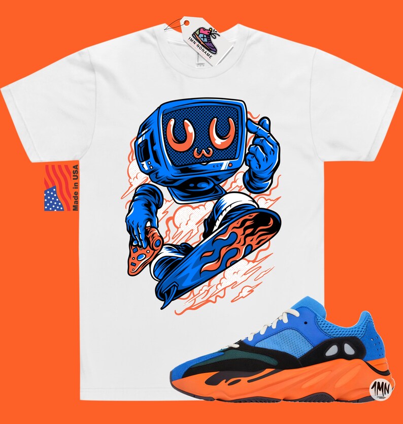 May include: White t-shirt with a cartoon illustration of a blue robot holding a pizza and riding a blue and orange skateboard. The robot has a blue television screen for a head with a cartoon face. The t-shirt is paired with orange and blue sneakers with a black sole.