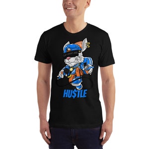 Puede incluir: Camiseta negra con un conejo de dibujos animados que lleva un sombrero azul, gafas de sol y una cadena de oro. El conejo sostiene un micr&oacute;fono y una lata de aerosol. El texto "HUSTLE" est&aacute; impreso en azul debajo del conejo.