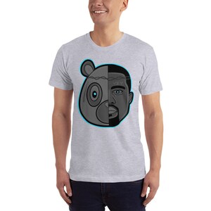 Op de afbeelding: Een grijs T-shirt met een afbeelding van een zwart-wit berenhoofd en het gezicht van Kanye West. Het gezicht van de beer bevindt zich aan de linkerkant van de afbeelding en het gezicht van Kanye West aan de rechterkant. De afbeelding is omrand met blauw.