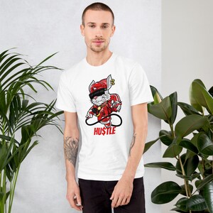 May include: White t-shirt with a cartoon rabbit wearing a red hat, sunglasses, and holding a microphone. The rabbit is standing on a red platform with the word "HUSTLE" written below it.