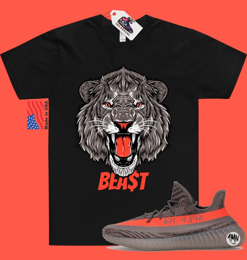 Puede incluir: Camiseta negra con un gr&aacute;fico de un le&oacute;n rugiente y la palabra "BEAST" en rojo. La camiseta se combina con zapatillas grises y naranjas con una raya negra.