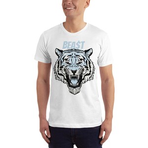 K&ouml;nnte beinhalten: Wei&szlig;es T-Shirt mit einem Aufdruck eines wei&szlig;en Tigerkopfes mit schwarzem Umriss und dem Wort "BEAST" in blauer Schrift &uuml;ber dem Tiger.