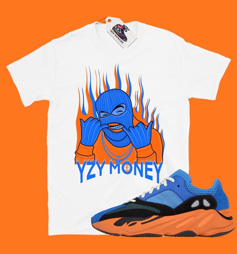 May include: White t-shirt with a blue and orange cartoon character wearing a ski mask and the text "YZY MONEY".  A pair of blue and orange sneakers are also pictured.