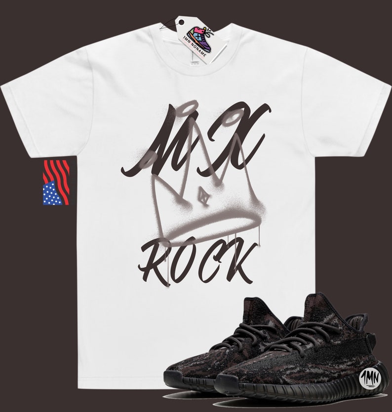 Puede incluir: Camiseta blanca con un gr&aacute;fico negro de una corona y el texto "MX ROCK". Un par de zapatillas negras y marrones con estampado de camuflaje se encuentran en la esquina inferior derecha de la imagen.