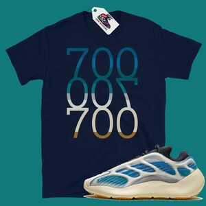 May include: A navy blue t-shirt with the numbers "700 007 700" printed in a gradient of blue, green, and brown. A pair of white and blue trainers with a black sole.